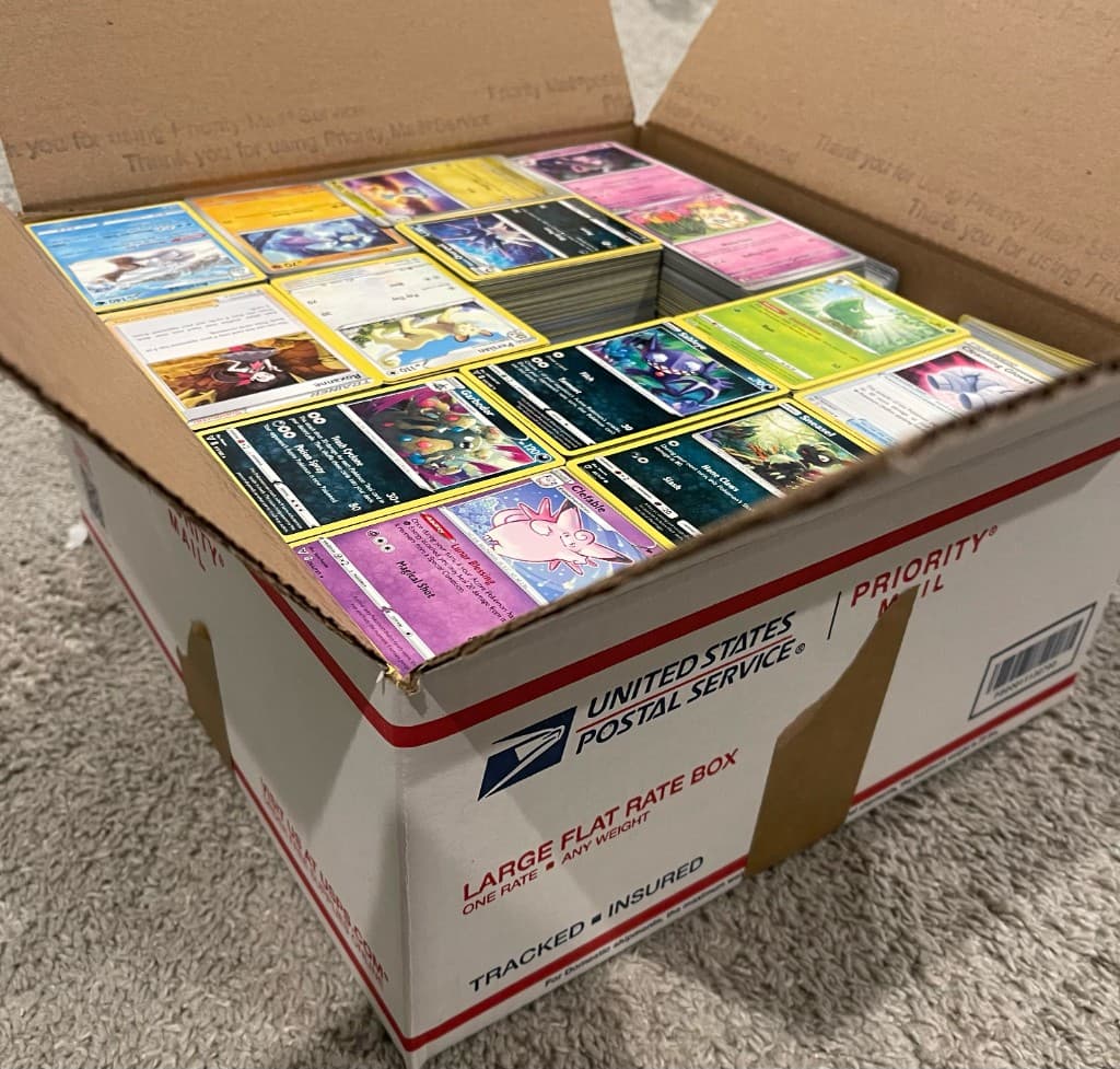 A USPS Priority Mail Large Flat Rate box packed full with stacks of Pokémon cards for outbound insured mail-in.